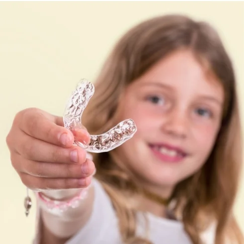 young girl hold clear aligner tray